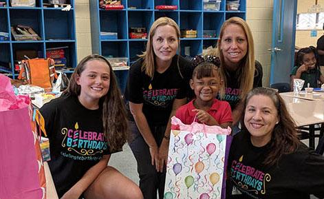 Four volunteers and one little girl with a gift bag